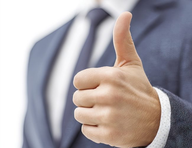 A businessman in a suit showing a thumbsup gesture, against a white background